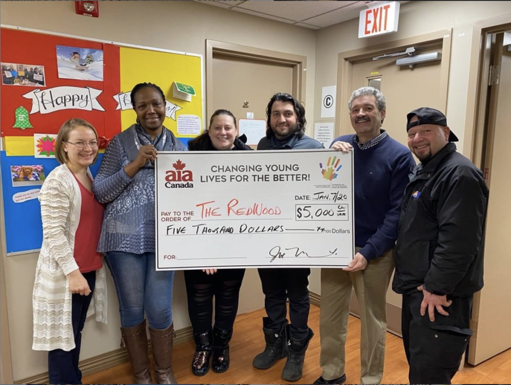 A group of people standing in front of a sign

Description automatically generated